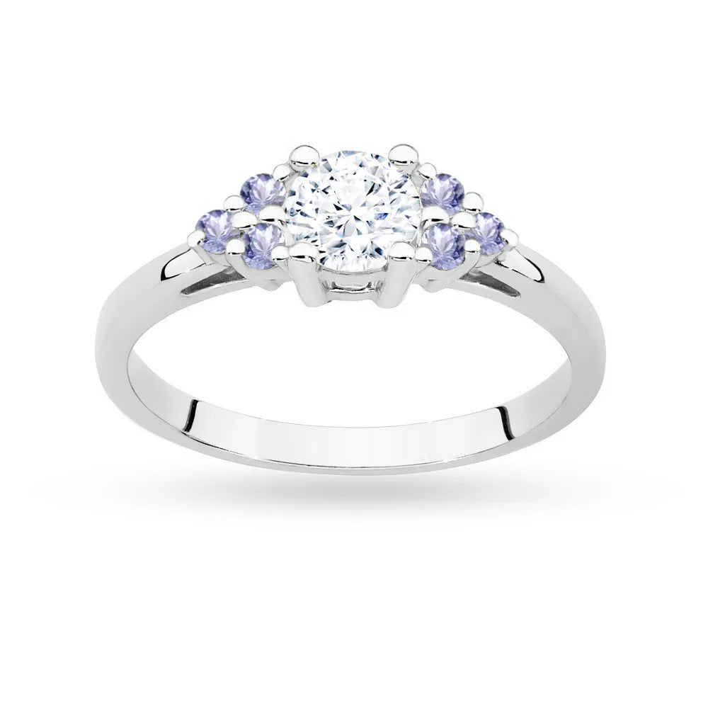 Prsten z bílého zlata 14k (585) s bílým safírem o hmotnosti 0,60 ct a 6 tanzanity. Je zabalen v elegantní krabičce, která je ideální jako dárek.