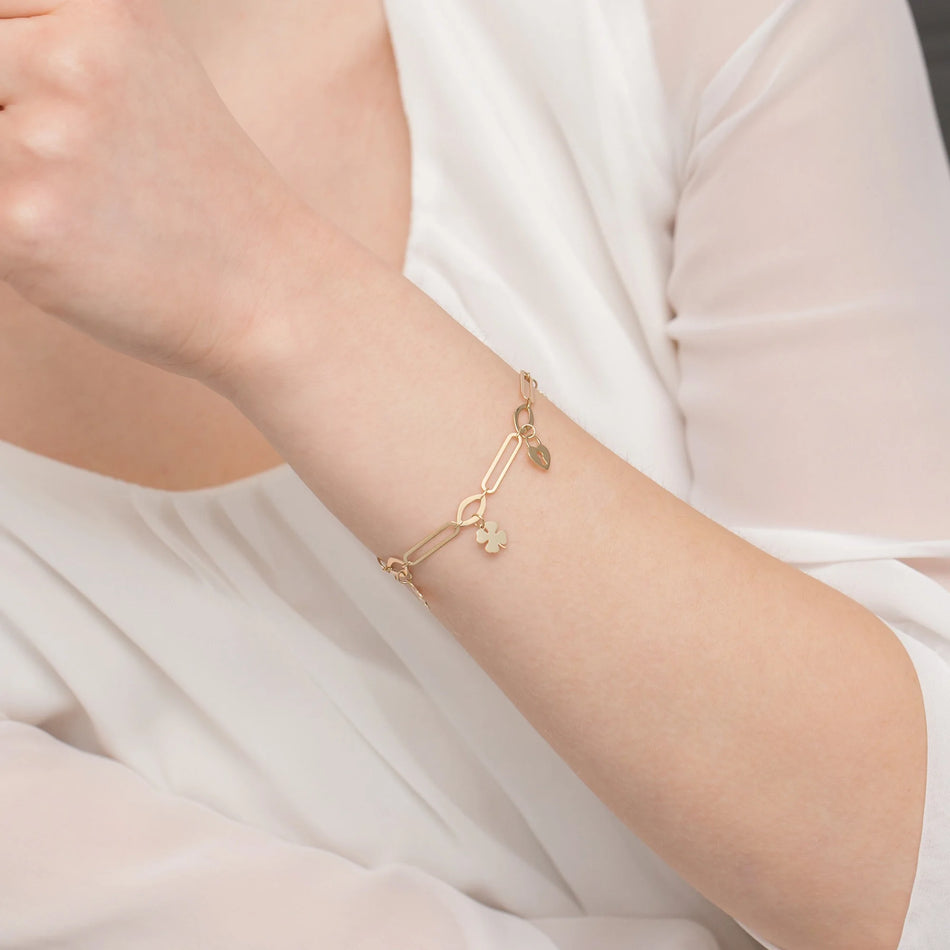 Zlatý náramek se širokými články a přívěsky zámek a čtyřlístek