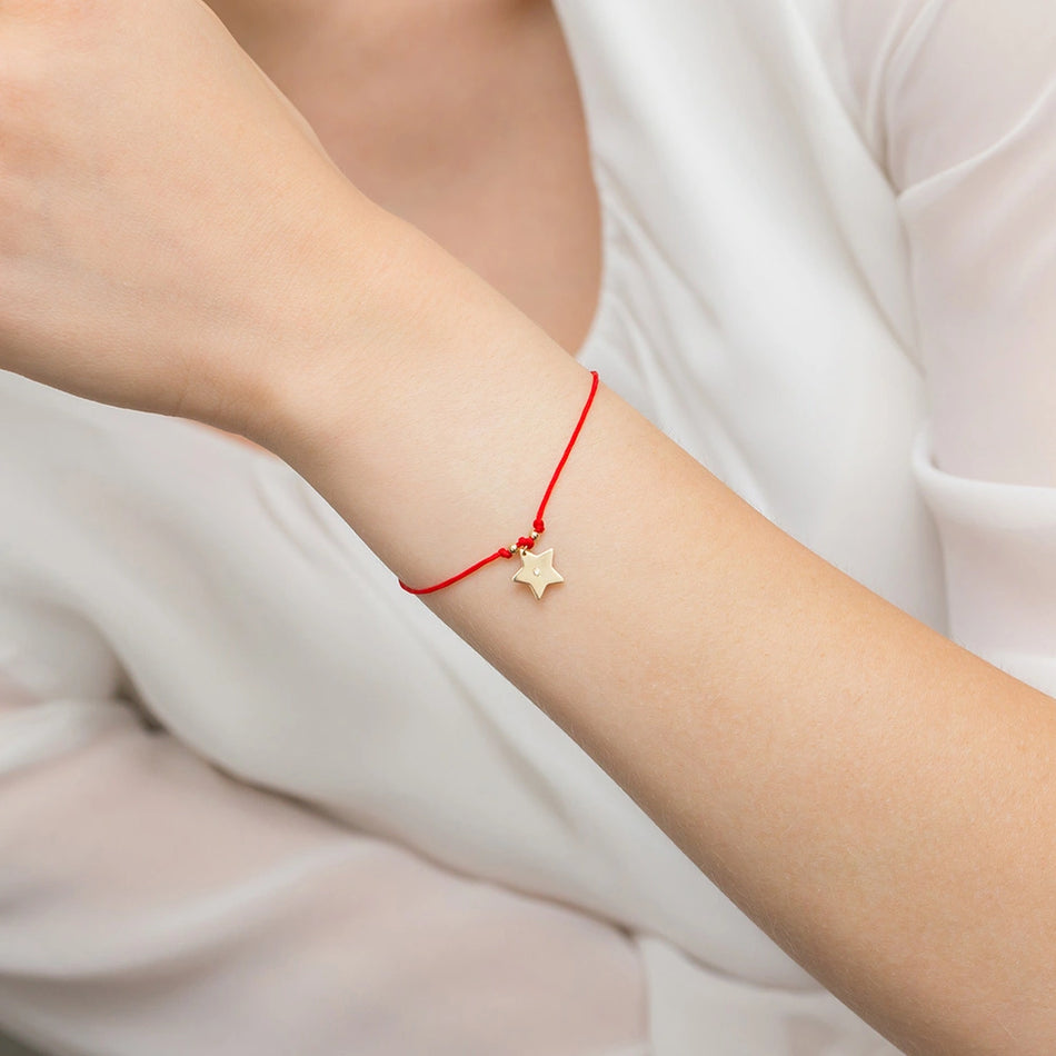 Zlatý náramek s diamantovou hvězdou na červeném provázku